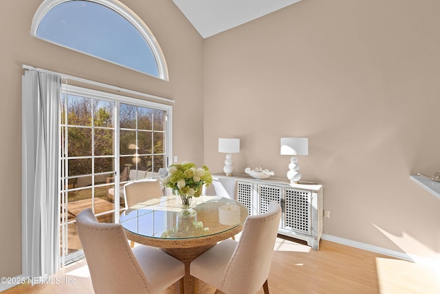 dining room with vaulted ceiling, wood finished floors, and baseboards