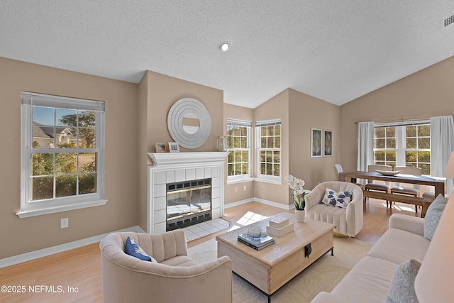 living room with lofted ceiling, plenty of natural light, and a tiled fireplace