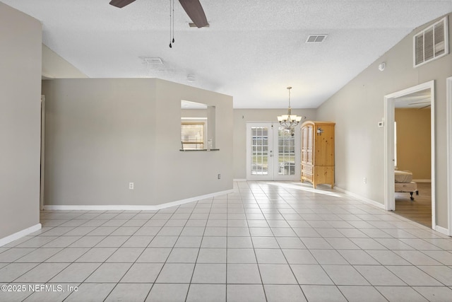 tiled empty room featuring french doors, ceiling fan with notable chandelier, and a textured ceiling