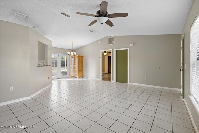 empty room featuring lofted ceiling, light tile patterned floors, french doors, and ceiling fan with notable chandelier