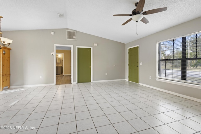 empty room featuring ceiling fan with notable chandelier, light tile patterned flooring, a textured ceiling, and vaulted ceiling