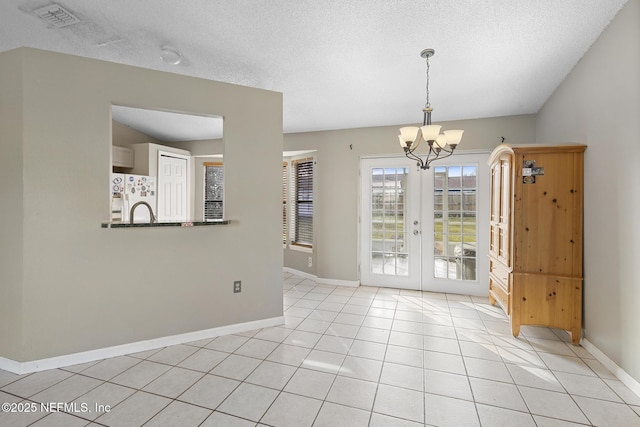 unfurnished dining area with an inviting chandelier, french doors, and light tile patterned flooring