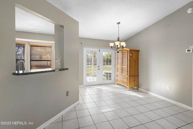 unfurnished dining area featuring a textured ceiling, an inviting chandelier, light tile patterned floors, and french doors