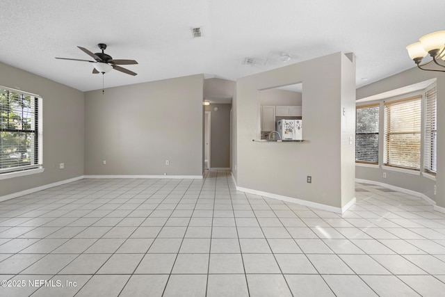 unfurnished living room with light tile patterned floors, sink, ceiling fan with notable chandelier, and a healthy amount of sunlight