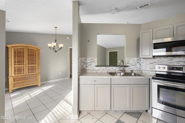 kitchen with light tile patterned floors, appliances with stainless steel finishes, decorative backsplash, a chandelier, and sink