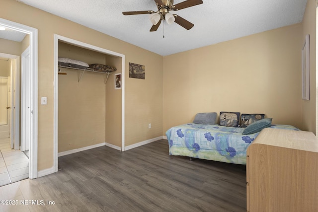 bedroom featuring ceiling fan, wood-type flooring, a closet, and a textured ceiling