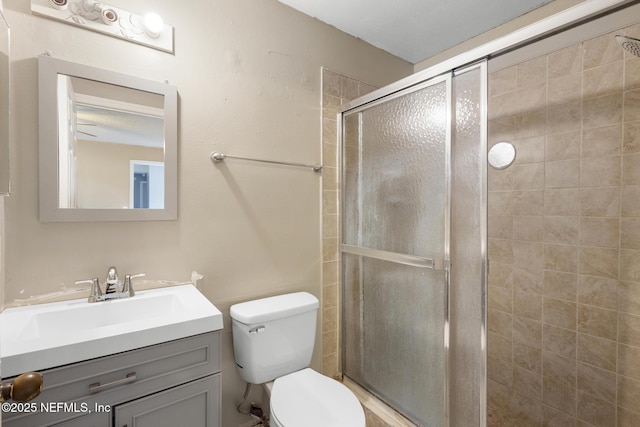 bathroom with a shower with shower door, vanity, and toilet