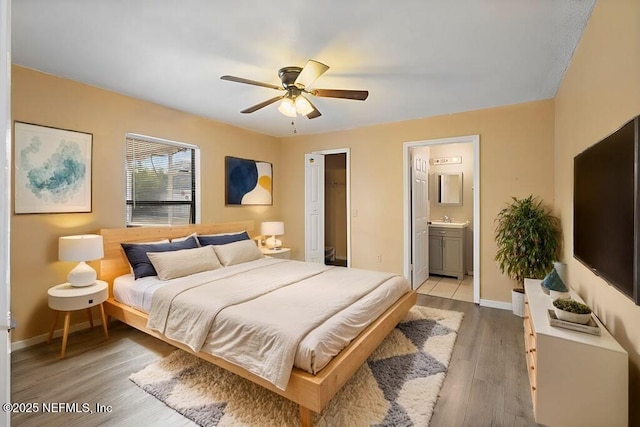 bedroom with ceiling fan, sink, wood-type flooring, and ensuite bath