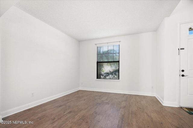 unfurnished room with wood finished floors, baseboards, and a textured ceiling