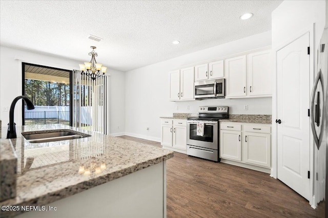 kitchen featuring a sink, dark wood-style floors, white cabinetry, appliances with stainless steel finishes, and a chandelier