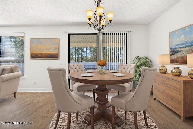 dining room featuring an inviting chandelier, baseboards, light wood finished floors, and a textured ceiling