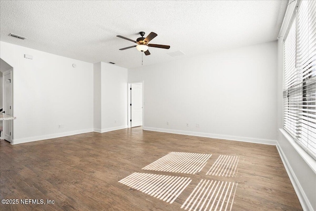 interior space with a wealth of natural light, visible vents, a textured ceiling, and wood finished floors