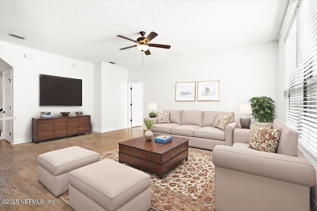 living area with ceiling fan, wood finished floors, visible vents, and a textured ceiling