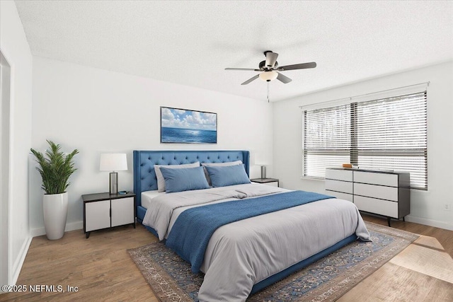 bedroom featuring a ceiling fan, wood finished floors, baseboards, and a textured ceiling