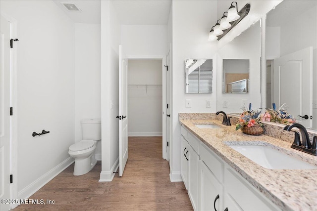 bathroom with toilet, wood finished floors, visible vents, and a sink