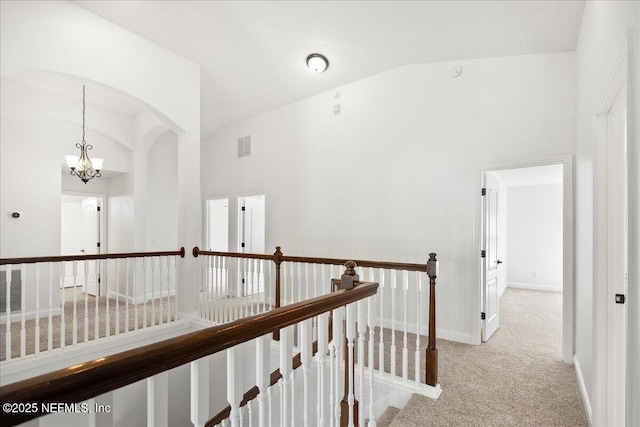 hallway with visible vents, an upstairs landing, high vaulted ceiling, an inviting chandelier, and carpet flooring