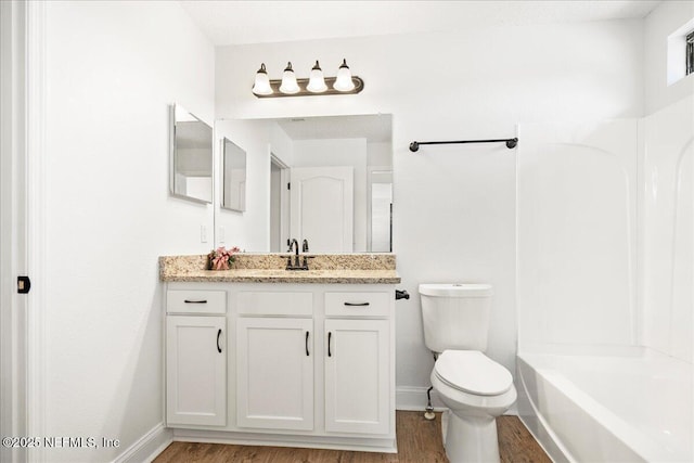 bathroom with toilet, vanity, baseboards, and wood finished floors