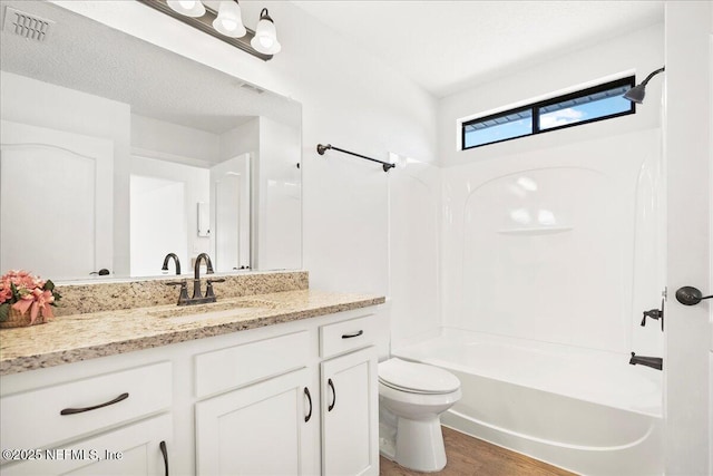 full bath with visible vents, washtub / shower combination, toilet, wood finished floors, and vanity