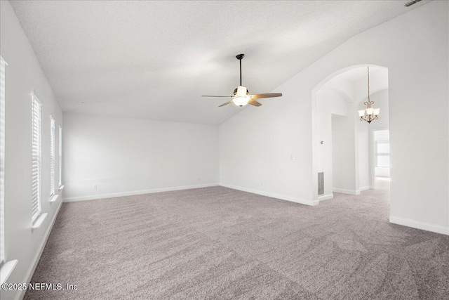 carpeted empty room with arched walkways, visible vents, a textured ceiling, and lofted ceiling