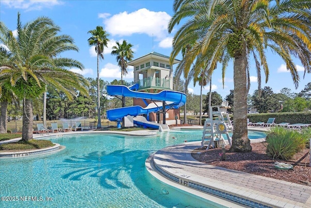 community pool featuring a patio, a water slide, and fence