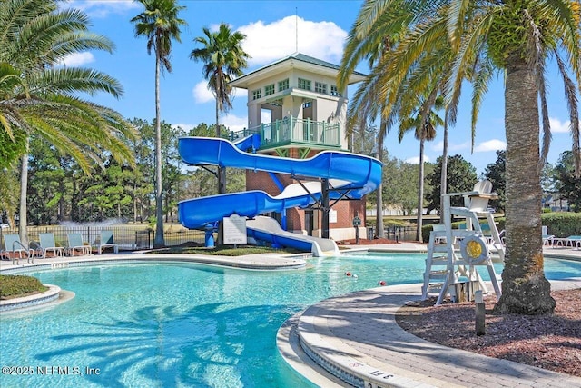 pool with a patio area, a water slide, and fence