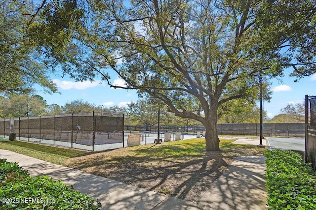 surrounding community with a tennis court and fence