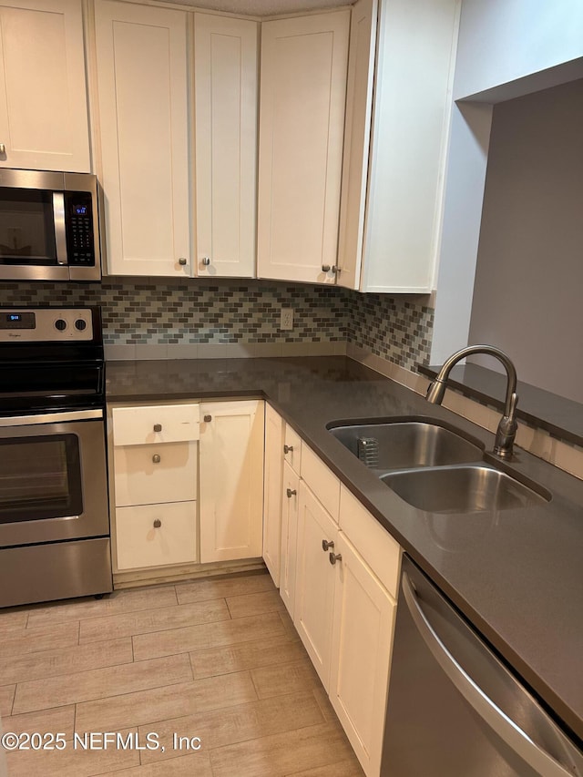 kitchen with stainless steel appliances, white cabinetry, sink, and light wood-type flooring