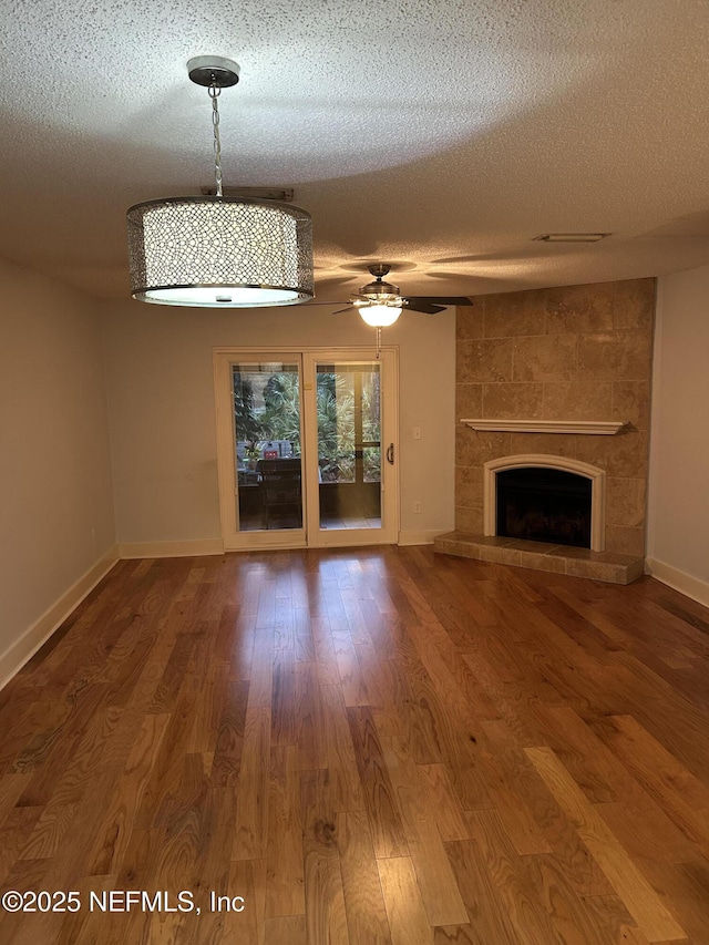 unfurnished living room with ceiling fan, wood-type flooring, a fireplace, and a textured ceiling