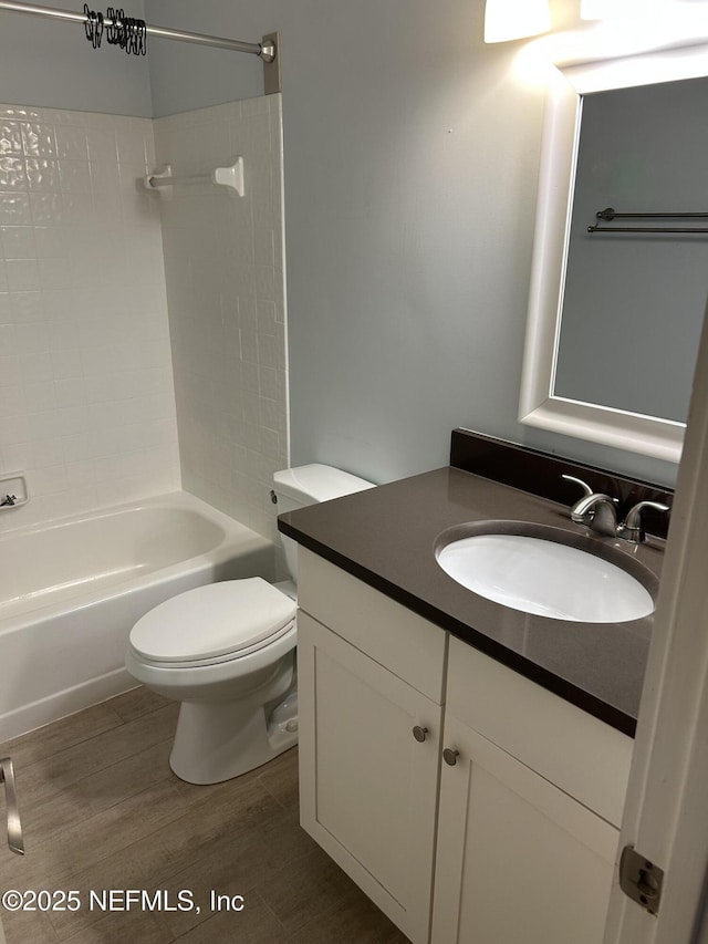 full bathroom featuring hardwood / wood-style flooring, vanity, toilet, and tiled shower / bath combo