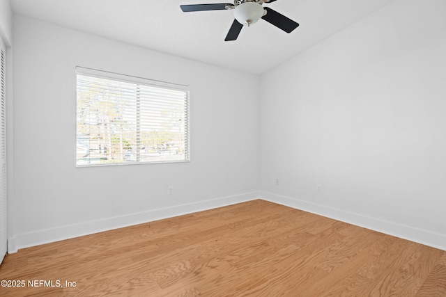 spare room featuring ceiling fan, light wood-style flooring, and baseboards