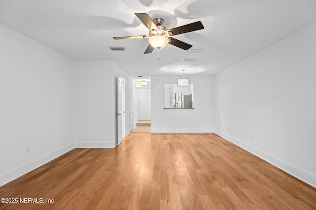 unfurnished room with light wood finished floors, baseboards, visible vents, ceiling fan, and a textured ceiling