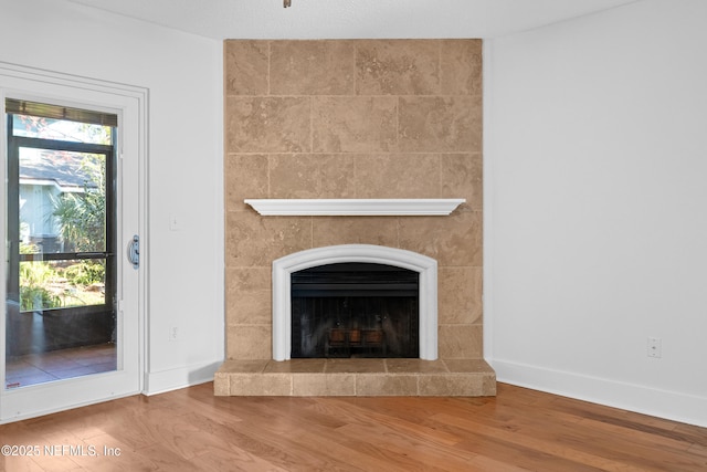 interior details featuring a tile fireplace, baseboards, and wood finished floors