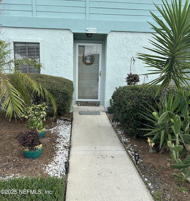 doorway to property featuring stucco siding