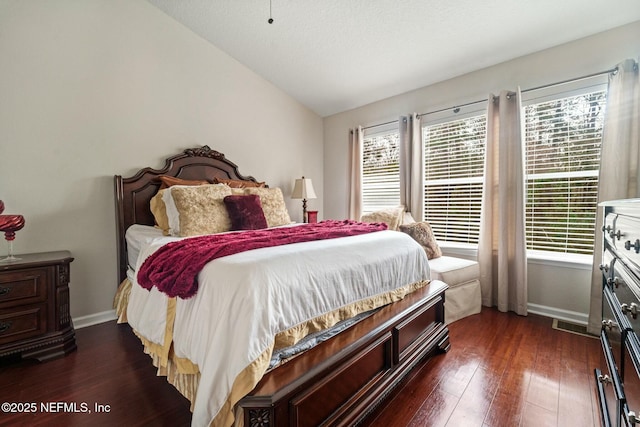 bedroom featuring multiple windows, vaulted ceiling, and dark hardwood / wood-style flooring