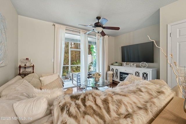 living room featuring ceiling fan, a textured ceiling, and hardwood / wood-style flooring