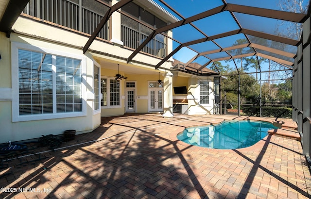 view of pool with french doors, a patio, ceiling fan, and glass enclosure