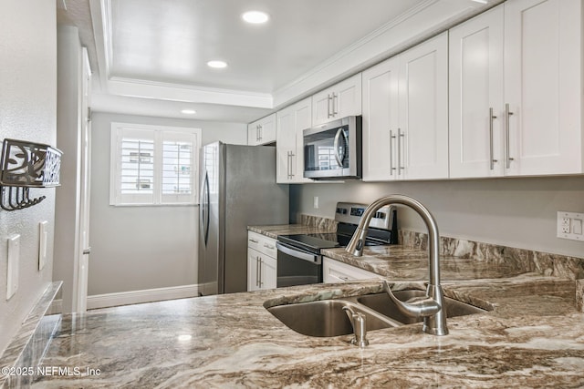 kitchen with sink, white cabinetry, light stone countertops, ornamental molding, and stainless steel appliances