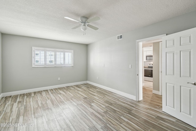 empty room with a textured ceiling, ceiling fan, and light hardwood / wood-style floors