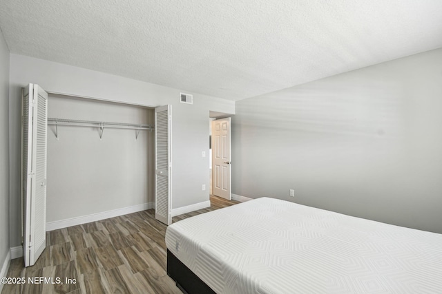 bedroom with dark wood-type flooring, a closet, and a textured ceiling