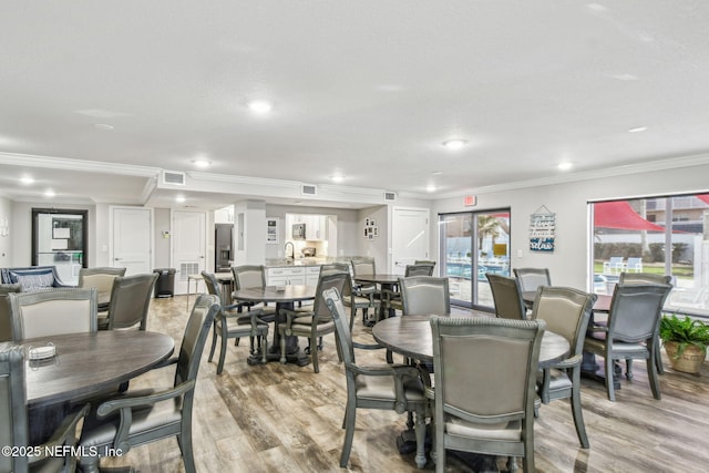 dining room with crown molding, a healthy amount of sunlight, and light wood-type flooring