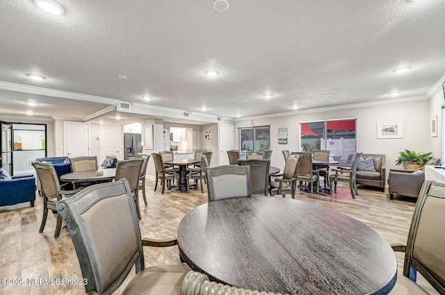 dining area featuring ornamental molding, a textured ceiling, and light wood-type flooring