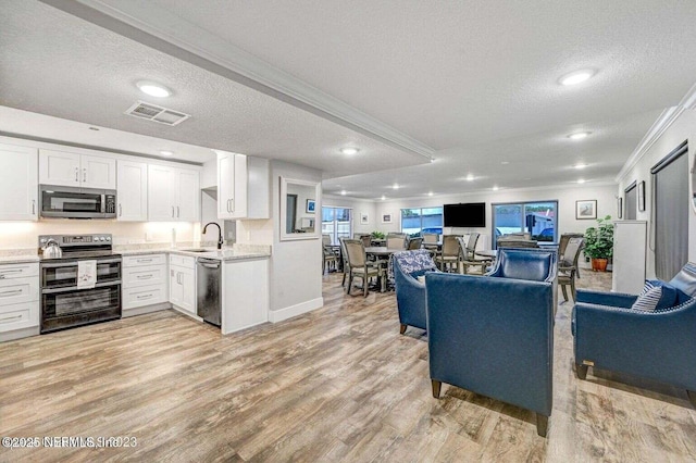 kitchen featuring crown molding, appliances with stainless steel finishes, light wood-type flooring, and white cabinets