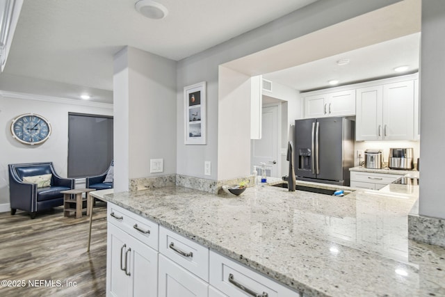 kitchen with dark hardwood / wood-style floors, stainless steel fridge with ice dispenser, light stone counters, and white cabinetry