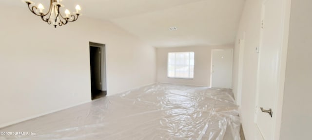 unfurnished room featuring vaulted ceiling and an inviting chandelier