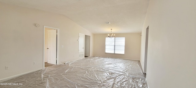 spare room featuring lofted ceiling, a chandelier, and a textured ceiling