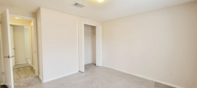 unfurnished bedroom with light colored carpet, a closet, and a textured ceiling