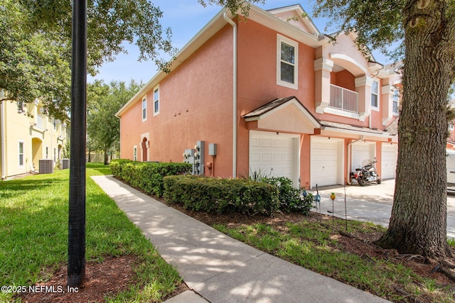 view of side of property featuring a lawn, central AC unit, and a garage