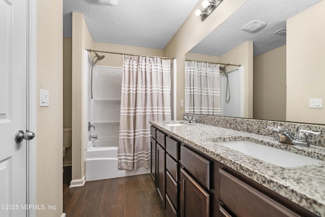 full bathroom with vanity, shower / bath combo, a textured ceiling, and hardwood / wood-style floors