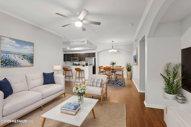 living room featuring ceiling fan, dark wood-type flooring, and crown molding