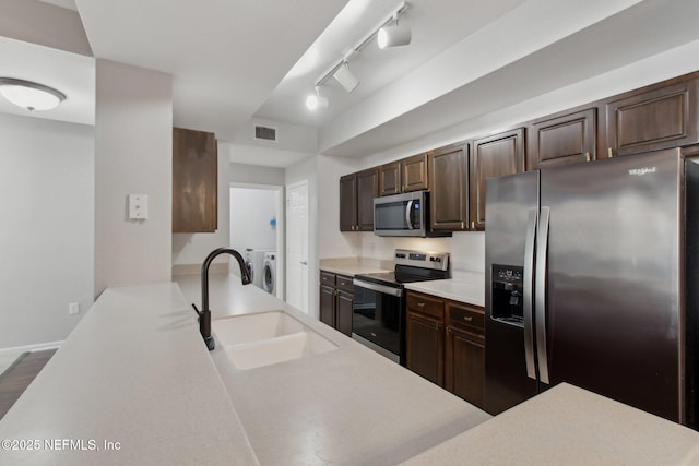 kitchen featuring appliances with stainless steel finishes, sink, separate washer and dryer, and dark brown cabinets